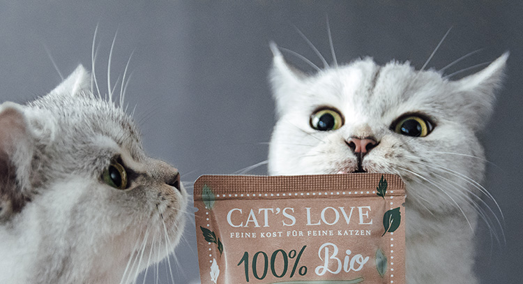 Zwei Katzen die an einer Bio Pouch von CAT'S LOVE schnuppern